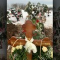 Остављене бела марама и руже на крсту Тужна сцена на гробљу након сахране Матије Радуловића, естрадног фризера који је…