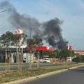 Požar na krovu zgrade u Novom Sadu. Kulja gust crni dim, ekipe vatrogasaca na terenu.